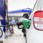 white car refueling gasoline by auto dispenser nozzle petrol station with warm sunlight
