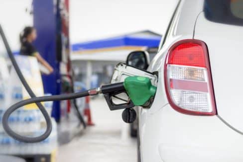 white car refueling gasoline by auto dispenser nozzle petrol station with warm sunlight
